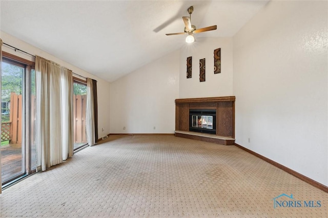 unfurnished living room with carpet, a glass covered fireplace, vaulted ceiling, baseboards, and ceiling fan