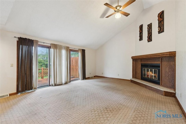 unfurnished living room featuring carpet, baseboards, vaulted ceiling, a ceiling fan, and a glass covered fireplace