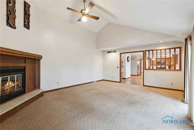 unfurnished living room featuring carpet floors, lofted ceiling, a ceiling fan, a glass covered fireplace, and baseboards