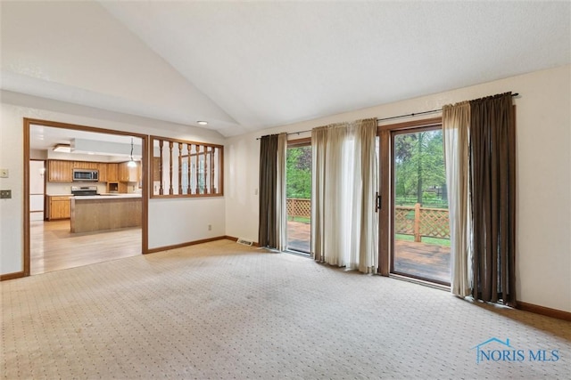 unfurnished living room featuring light colored carpet, baseboards, and vaulted ceiling