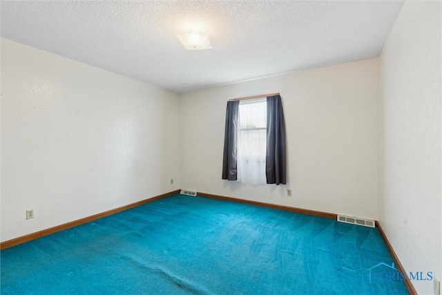 carpeted spare room featuring a textured ceiling and baseboards