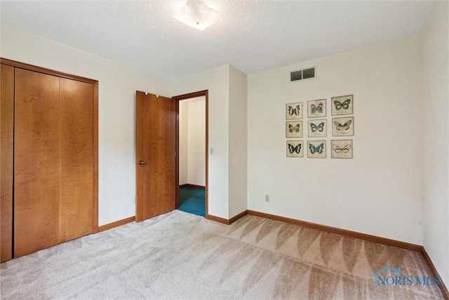 unfurnished bedroom featuring carpet, a textured ceiling, baseboards, and a closet