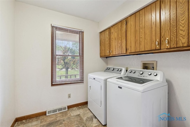 laundry room featuring washer and clothes dryer, cabinet space, baseboards, and light stone finish flooring