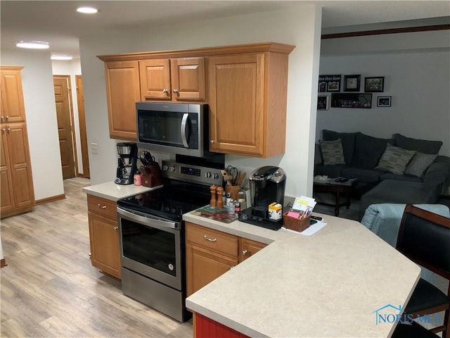 109 Rivers Edge Ln Unit C, Upper Sandusky, OH 43351 - kitchen featuring stainless steel appliances, a peninsula, light countertops, open floor plan, and light wood finished floors