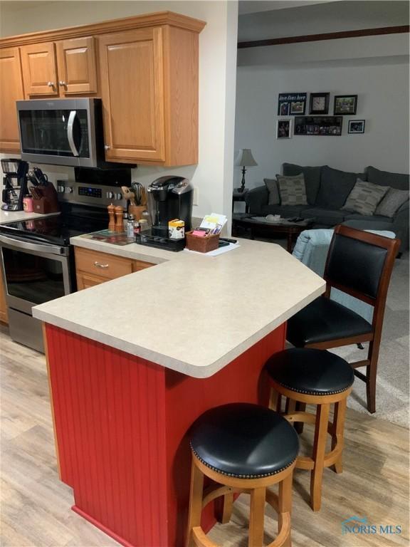 109 Rivers Edge Ln Unit C, Upper Sandusky, OH 43351 - kitchen featuring appliances with stainless steel finishes, light wood-type flooring, a kitchen bar, and light countertops