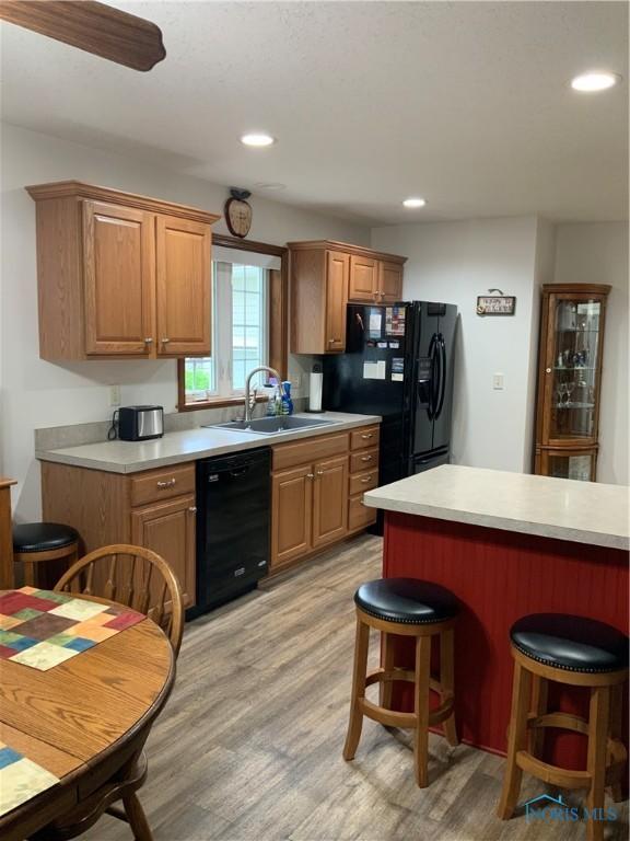 109 Rivers Edge Ln Unit C, Upper Sandusky, OH 43351 - kitchen with black appliances, a sink, a breakfast bar area, light wood-style flooring, and recessed lighting
