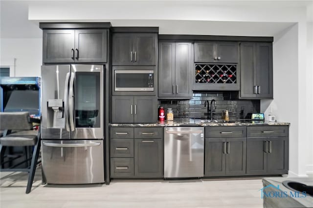 8440 E Woodland Trl, Findlay, OH 45840 - kitchen featuring stainless steel appliances, stone counters, tasteful backsplash, a sink, and light wood-style flooring