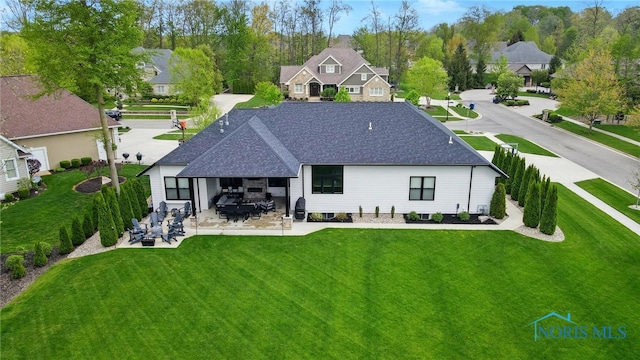 8440 E Woodland Trl, Findlay, OH 45840 - back of property with a shingled roof, a yard, a patio area, a residential view, and outdoor dining space
