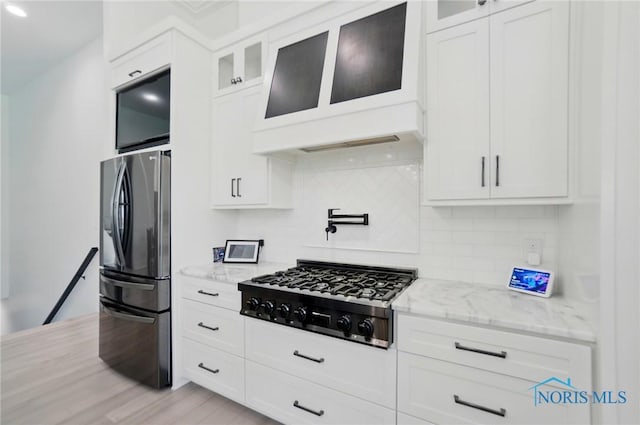 8440 E Woodland Trl, Findlay, OH 45840 - kitchen with stainless steel fridge with ice dispenser, black gas cooktop, light stone counters, tasteful backsplash, and white cabinetry