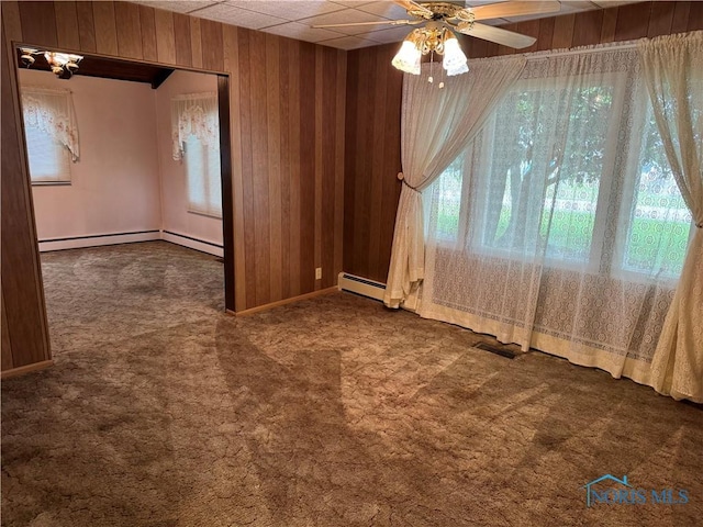 165 5th St, Mcclure, OH 43534 - carpeted spare room featuring a baseboard heating unit, wooden walls, and a ceiling fan