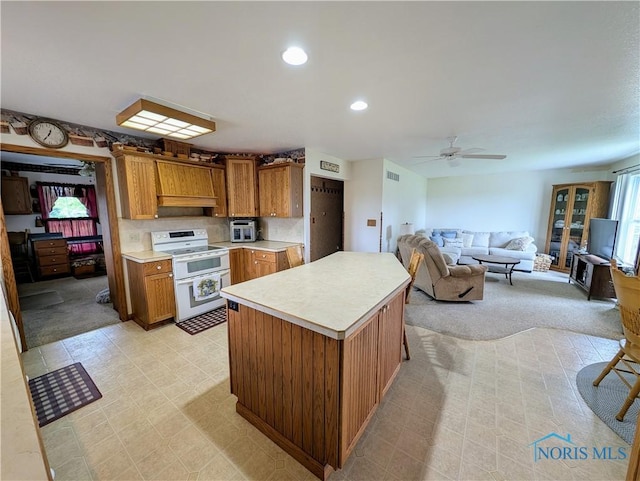 2450 N Billman Rd, Genoa, OH 43430 - kitchen featuring double oven range, light countertops, brown cabinetry, a center island, and a ceiling fan