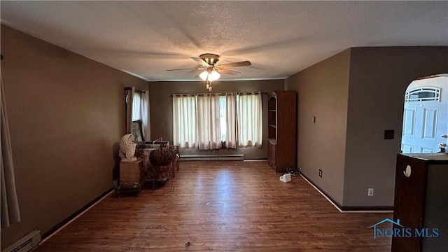 203 E Ash St, Continental, OH 45831 - unfurnished room featuring wood finished floors, ceiling fan, a baseboard heating unit, arched walkways, and a baseboard radiator