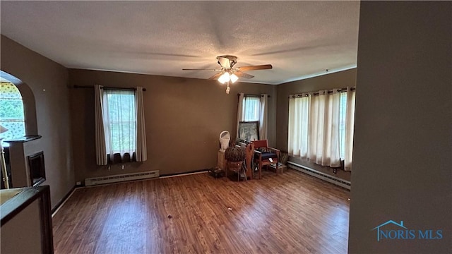 203 E Ash St, Continental, OH 45831 - spare room with a baseboard radiator, arched walkways, ceiling fan, and wood finished floors