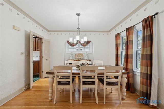 dining space featuring a chandelier, light wood finished floors, ornamental molding, and baseboards