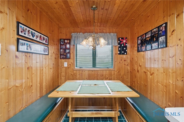 dining room with tile patterned flooring, wooden walls, and wood ceiling