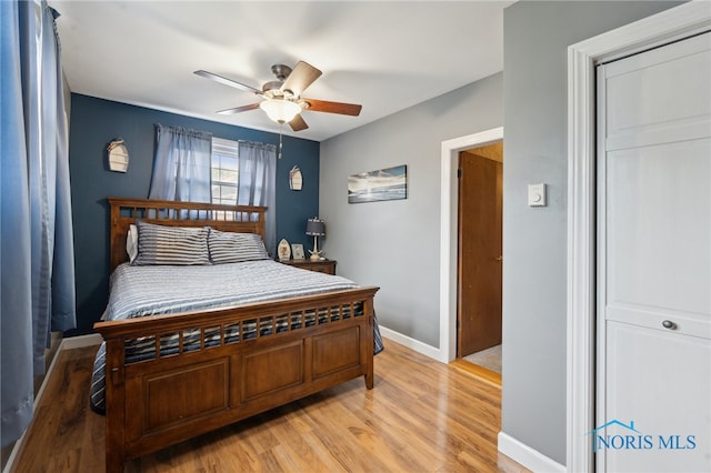 bedroom with light wood finished floors, a ceiling fan, and baseboards