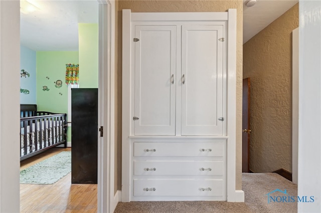 hallway with a textured wall and light wood-style floors