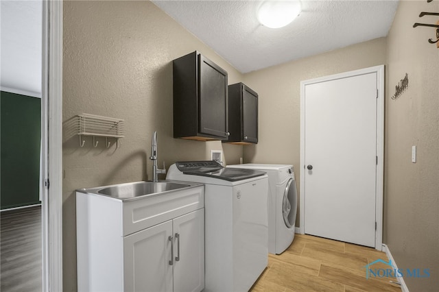 7060 Joannes Way, Maumee, OH 43537 - washroom featuring cabinet space, light wood-style floors, washer and dryer, a textured ceiling, and a textured wall