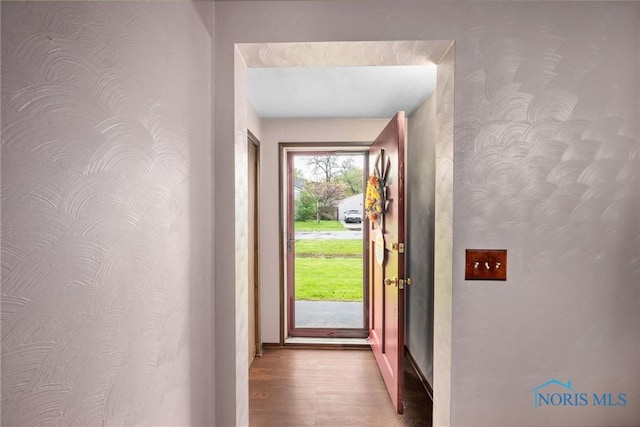 entryway featuring wallpapered walls, wood finished floors, and baseboards