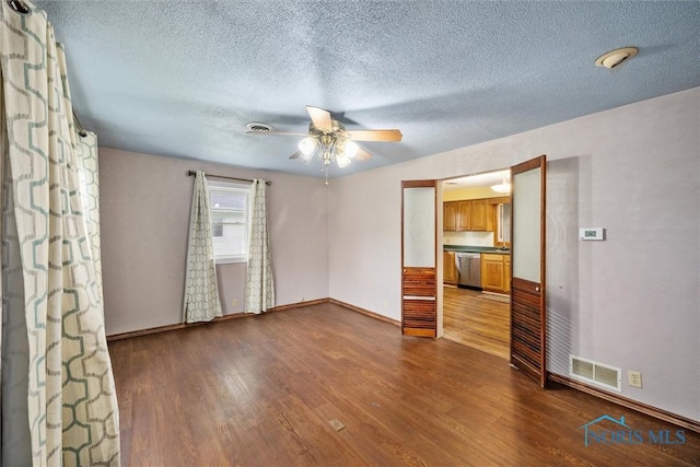 empty room with ceiling fan, dark wood finished floors, baseboards, and a textured ceiling