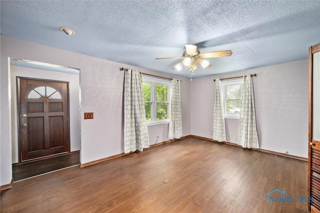 foyer with wood finished floors, a ceiling fan, a textured ceiling, and baseboards