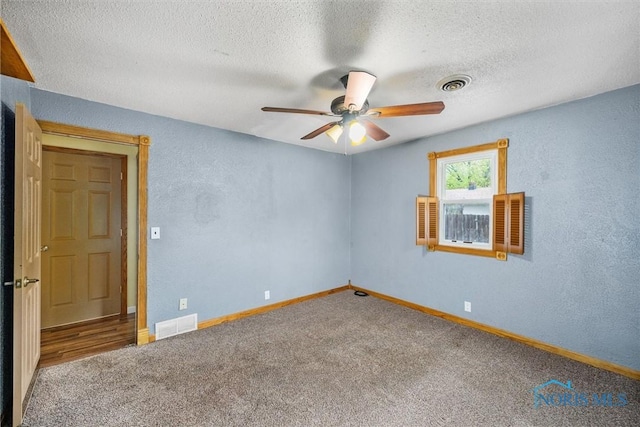carpeted empty room with ceiling fan, baseboards, a textured ceiling, and a textured wall