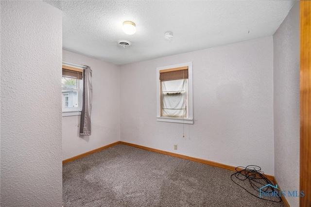 spare room featuring carpet flooring, baseboards, a textured ceiling, and a textured wall