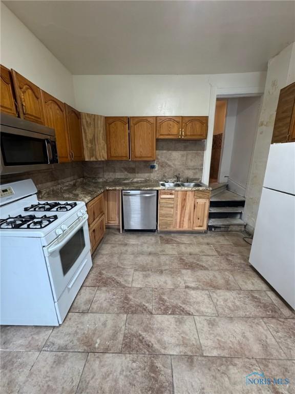 2108 N Michigan St, Toledo, OH 43611 - kitchen with stainless steel appliances, a sink, brown cabinets, and decorative backsplash