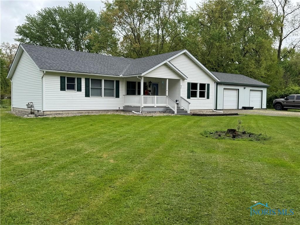 single story home with covered porch, an attached garage, driveway, and a front yard