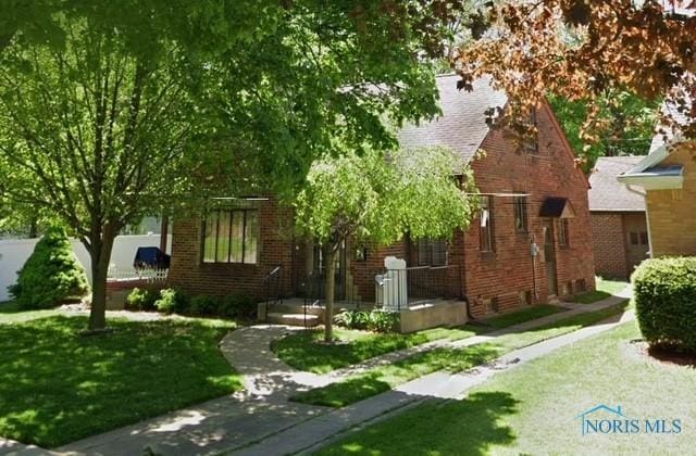 view of front of property with a front lawn and brick siding