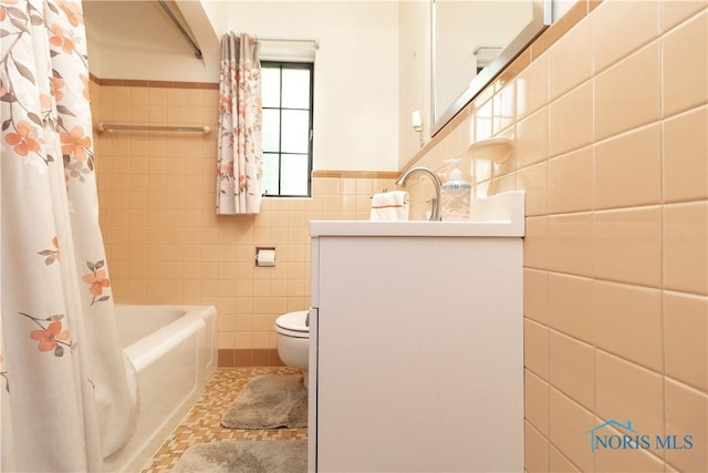 bathroom featuring tile walls, vanity, toilet, wainscoting, and shower / bath combo