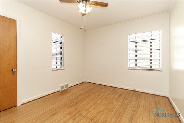 spare room featuring light wood-type flooring, ceiling fan, and baseboards