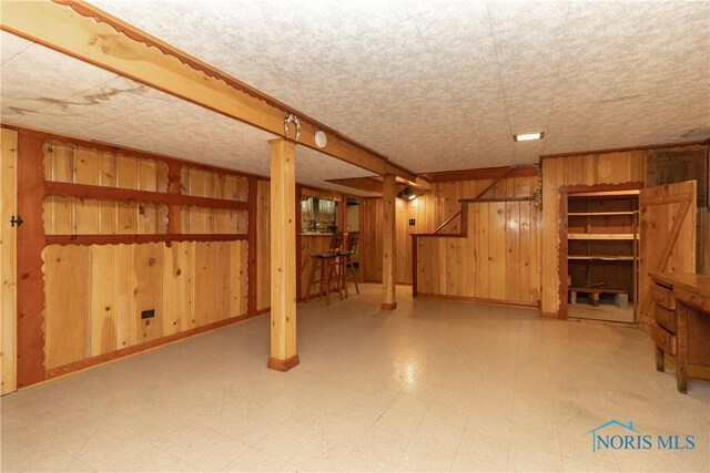 finished below grade area featuring wooden walls and tile patterned floors