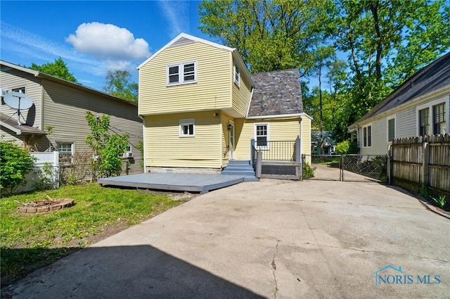 back of house with fence, a wooden deck, and a fire pit