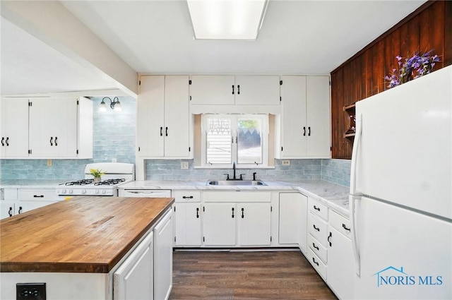 kitchen featuring white appliances, a sink, backsplash, white cabinets, and butcher block countertops