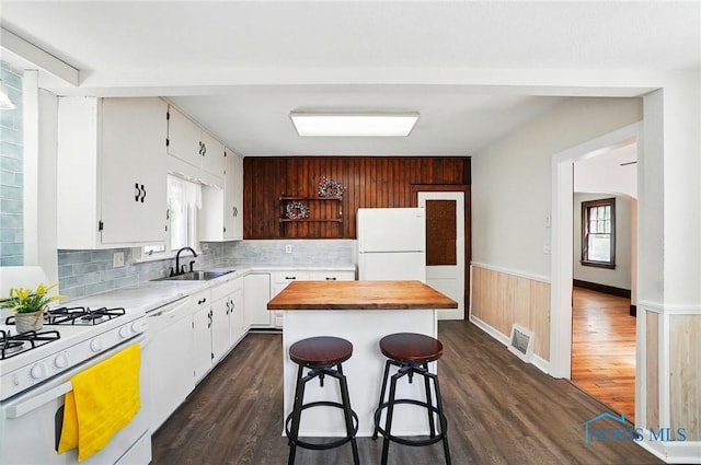 kitchen featuring a sink, white appliances, dark wood finished floors, decorative backsplash, and white cabinets