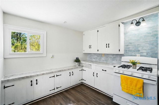 kitchen with white gas range oven, tasteful backsplash, white cabinetry, dark wood-style flooring, and light stone countertops