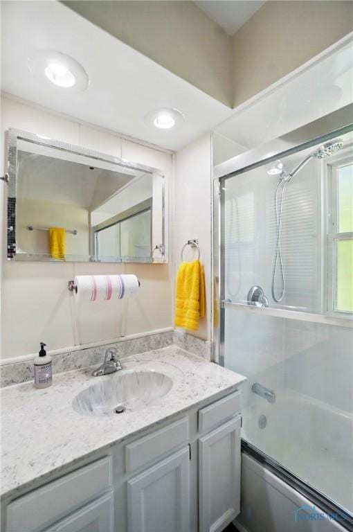 full bath featuring vanity and bath / shower combo with glass door
