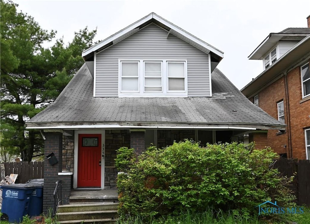 335 Suder Ave, Toledo, OH 43611 - view of front facade featuring fence, roof with shingles, and stone siding