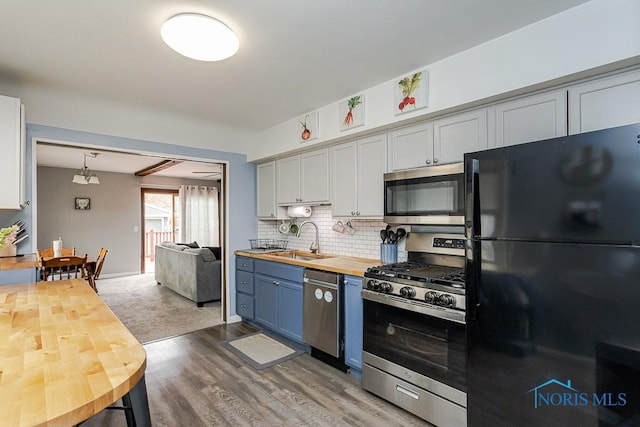3134 Cragmoor Ave, Toledo, OH 43614 - kitchen featuring appliances with stainless steel finishes, butcher block counters, a sink, decorative backsplash, and wood finished floors