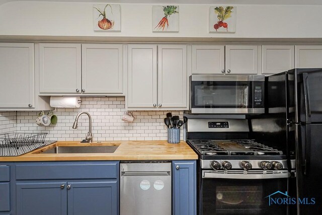 3134 Cragmoor Ave, Toledo, OH 43614 - kitchen featuring stainless steel appliances, butcher block countertops, a sink, decorative backsplash, and blue cabinets