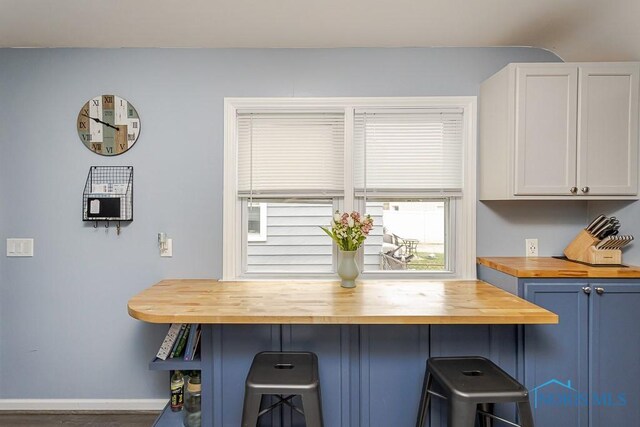 3134 Cragmoor Ave, Toledo, OH 43614 - kitchen with wooden counters, a breakfast bar, baseboards, and white cabinets