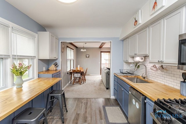 3134 Cragmoor Ave, Toledo, OH 43614 - kitchen featuring butcher block countertops, a sink, stainless steel dishwasher, blue cabinetry, and backsplash