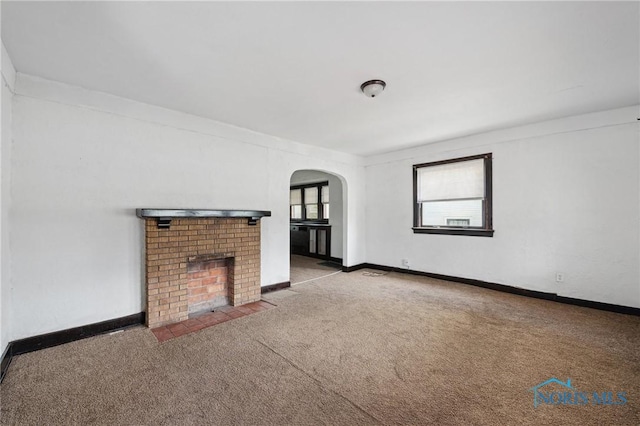 1908 Parkdale Ave, Toledo, OH 43607 - unfurnished living room with arched walkways, carpet flooring, a brick fireplace, and baseboards