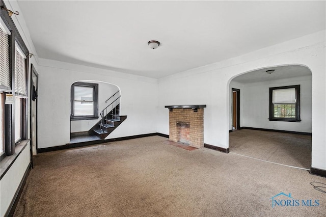 1908 Parkdale Ave, Toledo, OH 43607 - unfurnished room featuring a brick fireplace, plenty of natural light, carpet flooring, and arched walkways