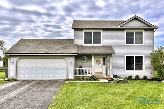 traditional-style house featuring driveway, a garage, a front lawn, and a shingled roof