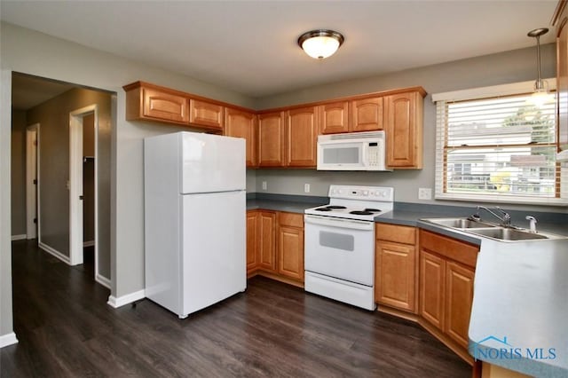 kitchen with white appliances, a sink, dark wood finished floors, and pendant lighting
