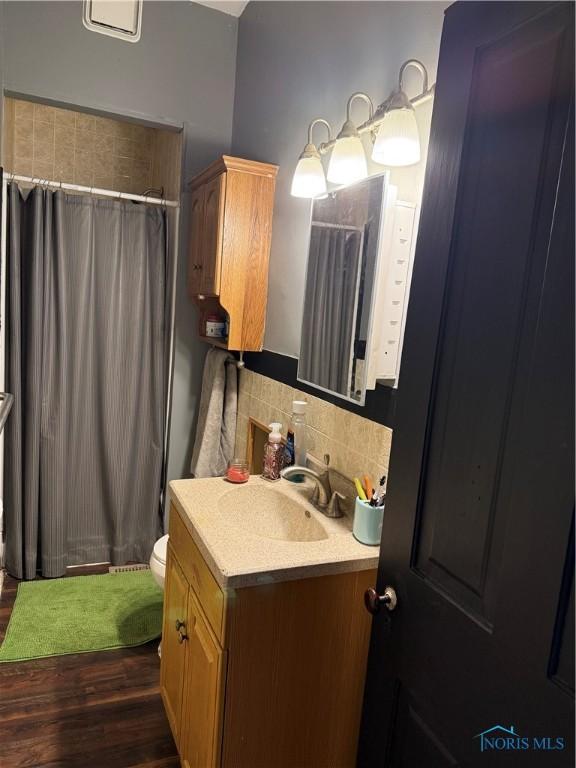 318 S Main St, North Baltimore, OH 45872 - bathroom with backsplash, vanity, wood finished floors, curtained shower, and toilet