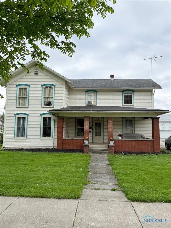 318 S Main St, North Baltimore, OH 45872 - view of front of home with covered porch, a front yard, and brick siding