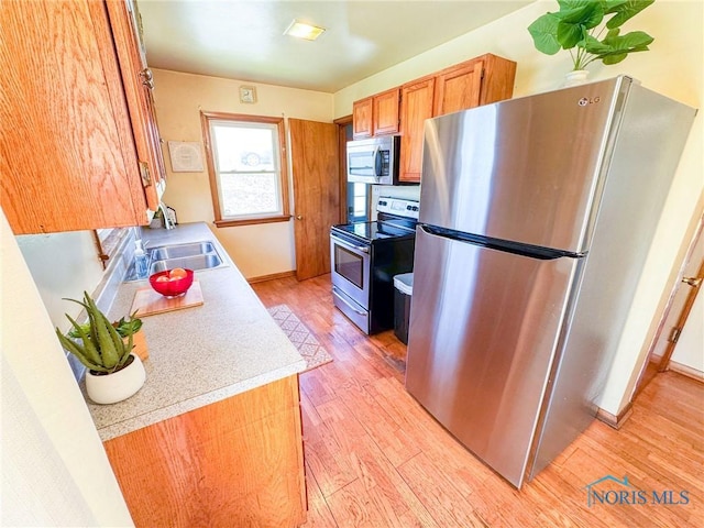 624 Myers St, Toledo, OH 43609 - kitchen with stainless steel appliances, a sink, light wood-style floors, light countertops, and brown cabinets